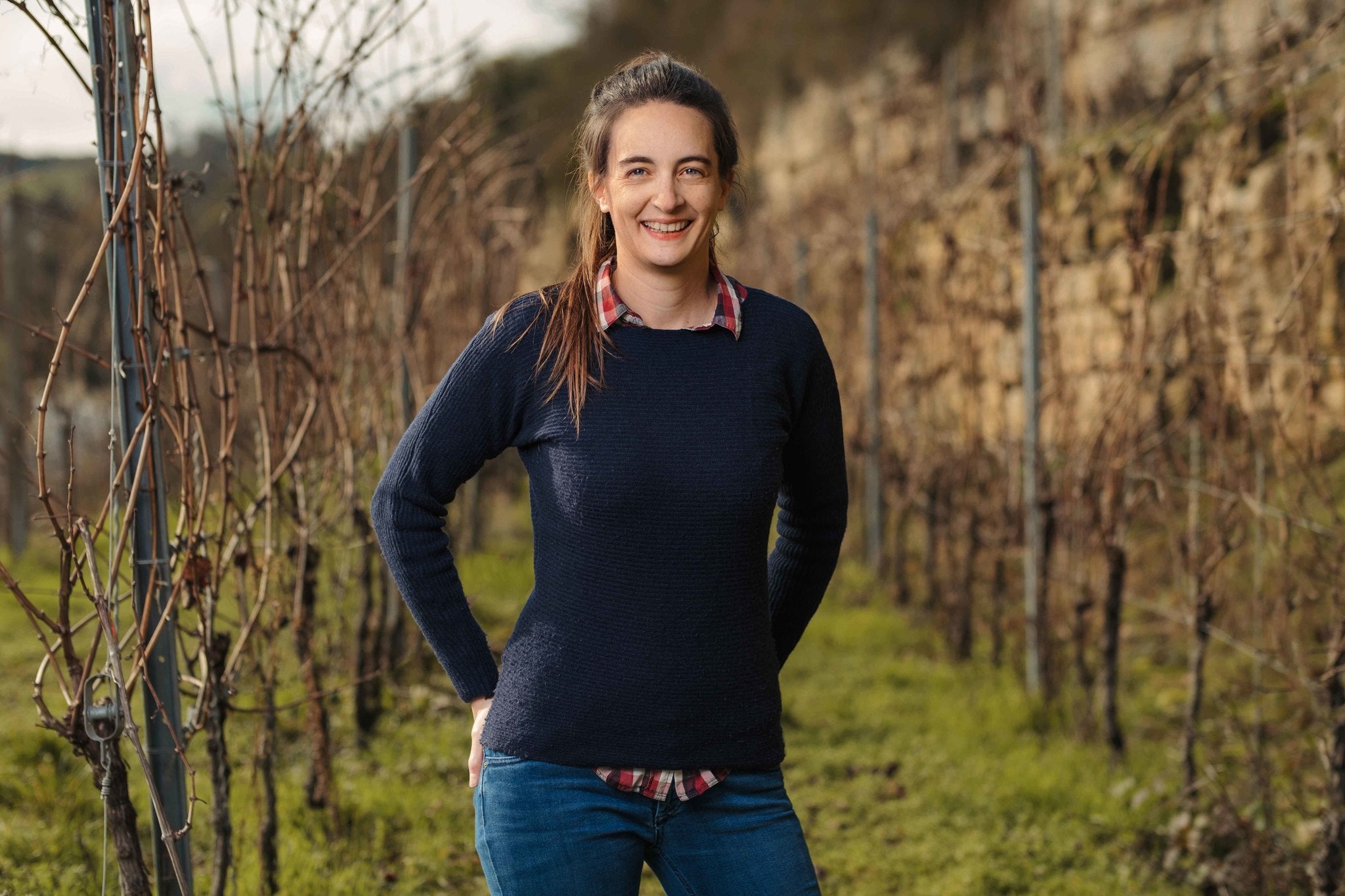 Corinne Kox, winemaker of Domaine L&R Kox, standing in front of her vineyard.